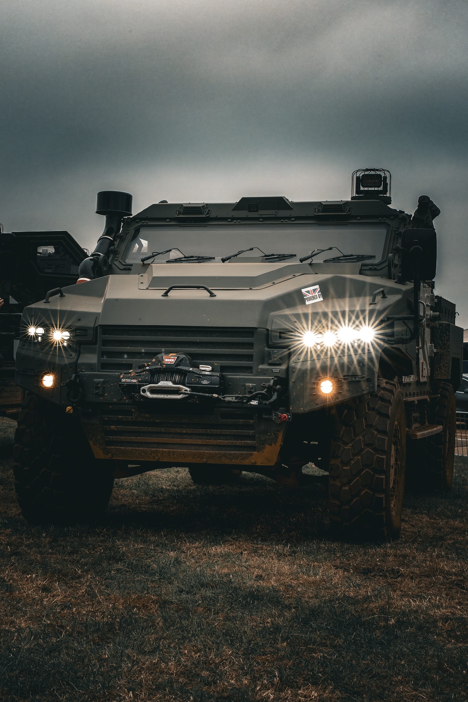 Protected vehicle under stormy sky with headlights on