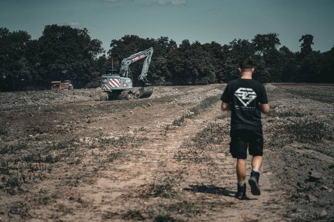 SkyGlide crew walking a groundworks site towards an excavator