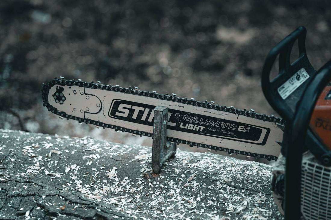 Chainsaw bar resting on fresh-cut timber covered in sawdust