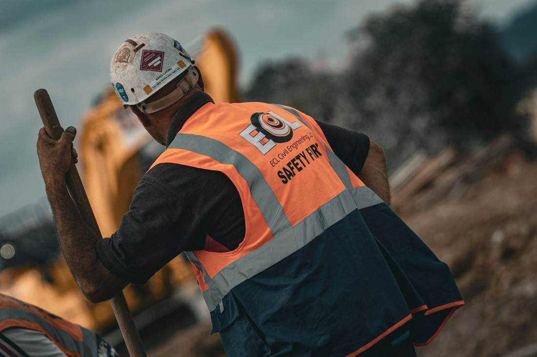 Civil engineering operative working ahead of an excavator